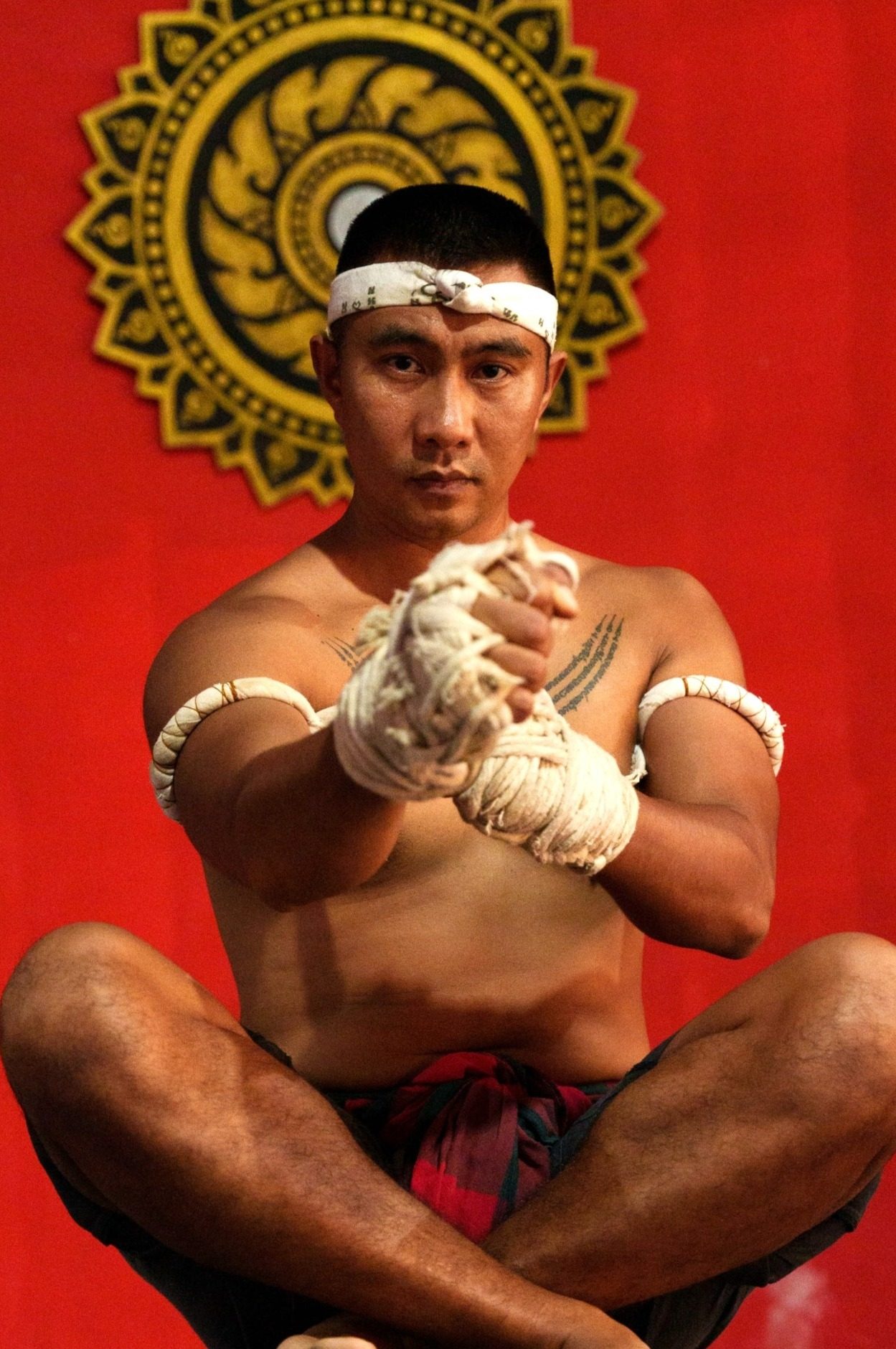 Kru Chane, founder of KMAX Gym, seated in mongkol and hand wraps